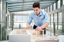 Young Businessman Or Architect With Model Of A House Standing In Office, Working.