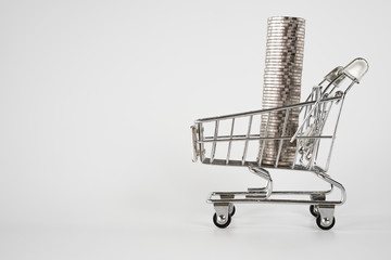 Row of coin money in shopping cart on a white background.