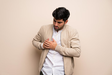 Wall Mural - Young man over isolated wall having a pain in the heart