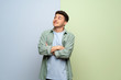 © luismolinero - Young man over blue and green background looking up while smiling
