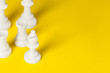 Chess figures on yellow background top view copy space