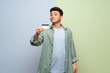 © luismolinero - Young man over blue and green background holding a credit card