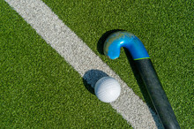 Field Hockey Stick And Ball On The Green Field