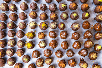 Group of sweet and tasty homemade chocolate balls on a backing paper sprinkled with different spice flavors close up