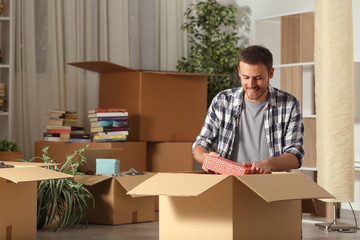 Canvas Print - Happy man moving home unboxing belongings in the night