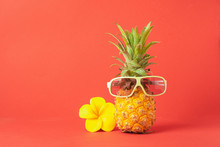 Yellow Ripe Pineapple In Sunglasses Red Bright Background. Funny Muzzle Of A Tropical Fruit. Concept Horizontal Frame.