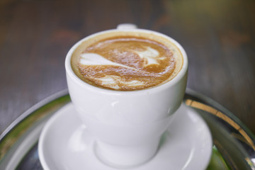 Cup of hot coffee latte on a wooden table