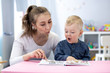 © Oksana Kuzmina - Speech therapist teaching letter pronunciation to kid boy in classroom