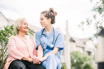 caregiver holding hand of happy elderly woman
