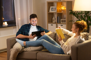 Sticker - leisure and people concept - happy couple with tablet computer and book at home in evening