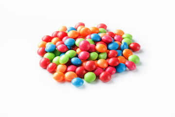 A rainbow of colors from multicolored candies close-up, multi-colored glaze dragee on a white background isolated