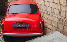 The Body Of A Red Car Stuck In A Brick Wall