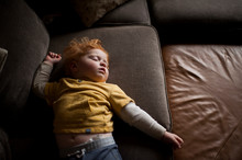 Young Boy Laying On Couch Napping At Home