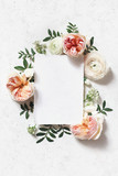 Feminine wedding, birthday mock-up scene. Blank paper greeting card. Floral frame of blush pink English roses, ranunculus flowers and lentisk leaves. Concrete table background. Flat lay, top view.