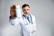 Smiling Doctor Holding Up A Bottle Of Tablets Or Pills With A Blank White Label For Treatment Of An Illness Or Injury.