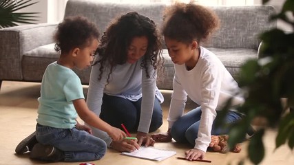 Wall Mural - Caring african mother drawing with colored pencils playing with kids