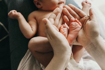 legs of a newborn baby in the arms of his mother