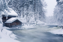 Old Wooden House Next To Rapids In Snowy Forest