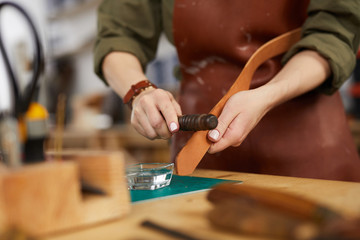 Wall Mural - Closeup of unrecognizable craftsman working with leather in tannery shop, copy space