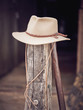 © PHILIPPE DEGROOTE/ADDICTIVE STOCK - Traditional cowboy hat placed on top of shabby lumber stake on blurred background of stable on ranch