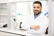 © Seventyfour - Smiling handsome young middle-eastern lab worker with beard in white coat crossing arms on chest and looking at camera in laboratory