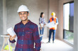 © Pormezz - Portrait male engineer wearing safety helmet and holding blueprint in construction site.
