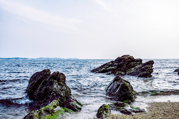 Sea shore and Large stones with blue sky. Dramatic seascape at sunset, Calm atmosphere beside coast of sea, Khao Laem Ya, Rayong Province, Thailand