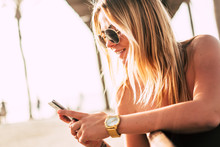 Young Millennial People Beautiful Golden Hair Blonde Girl Using Phone Internet Outdoor In A Sunny Perfect Day - Sunglasses And Summer Holiday Vacation Concept