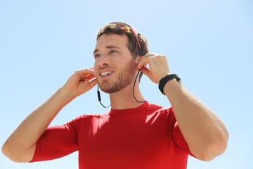 Wall Mural - Runner man getting ready for run putting on wireless earphones with bluetooth technology for headphones smartphone communication for listening music during running exercise. Happy athlete.