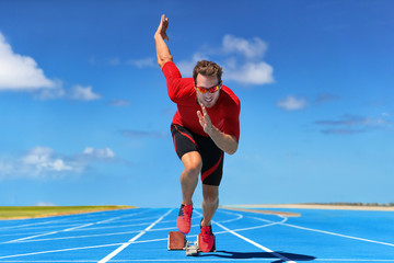 Runner athlete starting running at start of run track on blue running tracks at outdoor athletics and fiel stadium. Sprinter on race. Sport and fitness man sprinting.