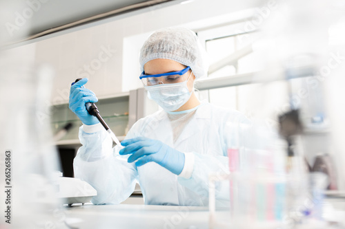Fotografía Serious concentrated female microbiologist in sterile clothing and safety goggle