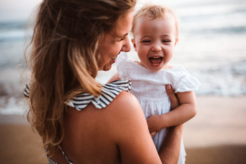 close-up of young mother with a toddler girl on beach on summer holiday.