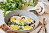 Fototapeta Kuchnia - fried eggs with bacon and dandelion leaves (dish with dandelion).  spring breakfast with first greens. dandelion-a useful edible flower, rich in vitamins.
