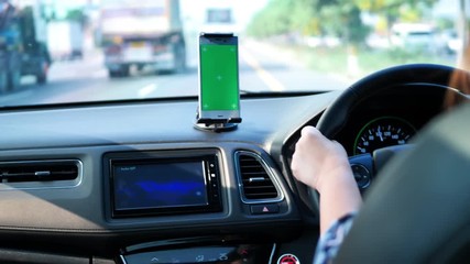 woman driving on the roads and the use of green-screen smart phone. See a map or listen to music.