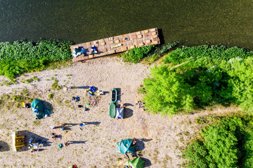 Camping tents on the beach. Tourists rafting on the river on a halt