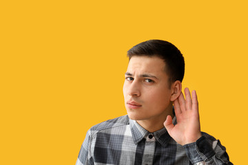 Young man with hearing problem on color background