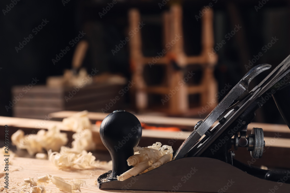Carpenter's smoothing plane on wooden plank in workshop