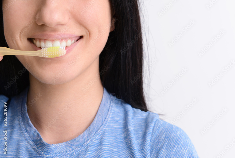 Woman with toothbrush on light background, closeup. Concept of dental hygiene