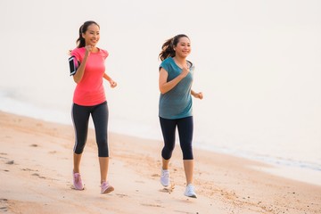 Portrait beautiful young sport asian woman running and exercise on the beach near sea and ocean at sunrise or sunset time