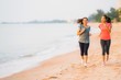 © siraphol - Portrait beautiful young sport asian woman running and exercise on the beach near sea and ocean at sunrise or sunset time