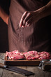 © petrrgoskov - Man cooking meat steaks on kitchen. Chef salt and pepper meat on wooden background