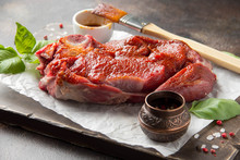 Raw beef on bone, cooking steak with spices, barbecue marinade, red sauce. Traditional food, uncooked meat on Board