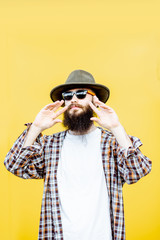 Wall Mural - Portrait of a cool stylish man in shirt and hat posing on the bright yellow background