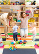 © Oksana Kuzmina - Babies toddlers playing with colorful educational toys together with mothers in nursery room