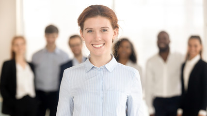 Young happy female leader looking in camera posing with team