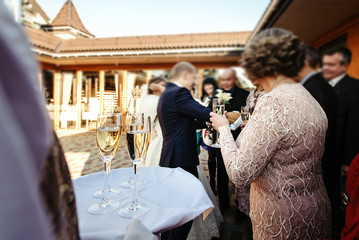 Wall Mural - waiter holding tray  with glasses of champagne for happy people toasting and cheering, celebrating wedding, luxury life concept