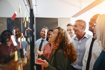 Wall Mural - Laughing businesspeople brainstorming with sticky notes on a gla