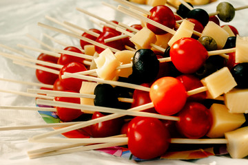 Wall Mural - cherry tomatoes olives cheese on wooden stick appetizer, picnic outdoors, catering buffet at summer celebration