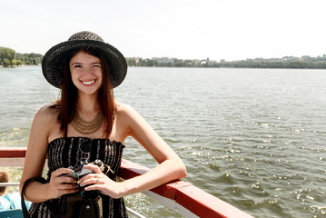 Wall Mural - happy stylish woman hipster holding photo camera and sailing on boat, summer travel concept, space for text