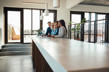 Wall Mural - Businesspeople laughing while working on a laptop in an office